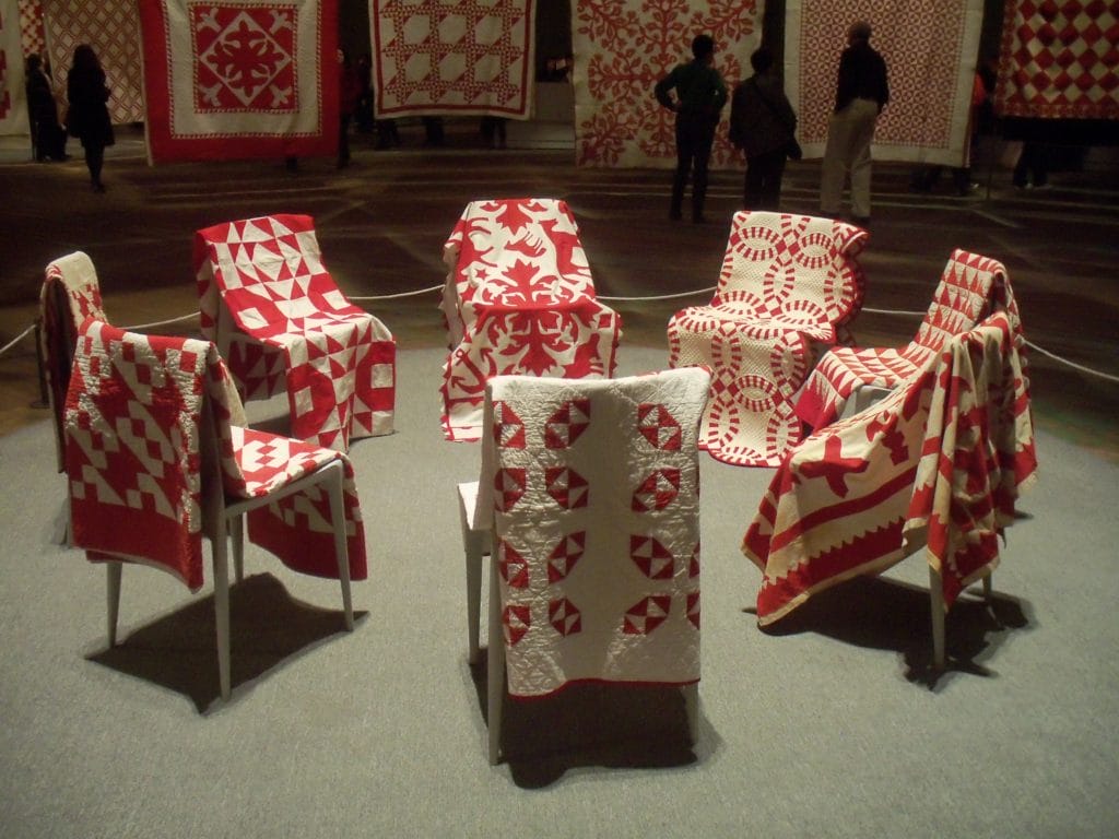 red and white quilts on chairs arranged in a circle