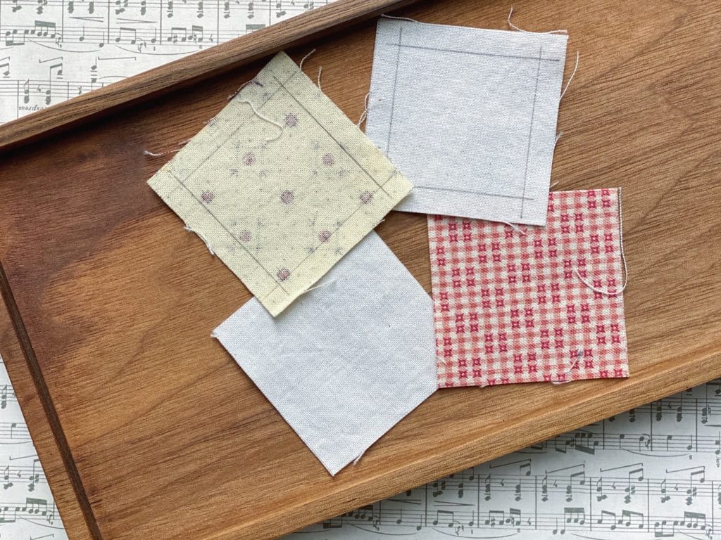 Two inch unfinished squares marked with 1/4" seam allowance in pencil