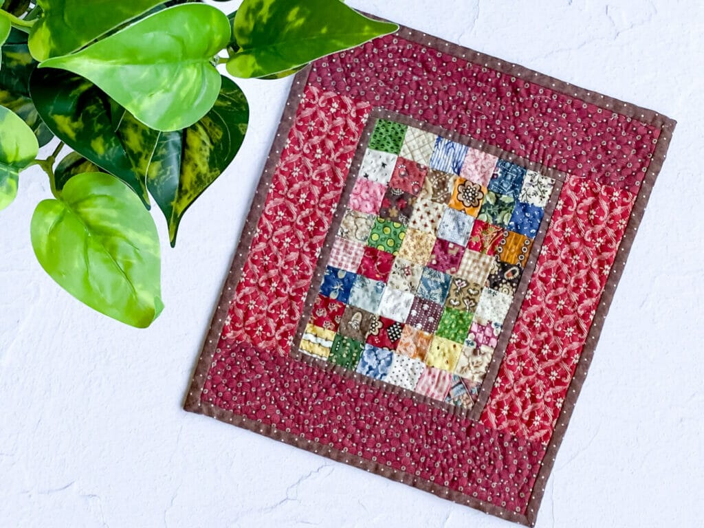 Scrappy quilt with 48 squares in center and red borders